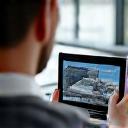 A professional using a tablet to review drone footage of a roof.